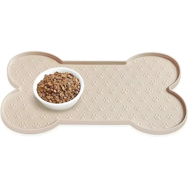 A beige silicone pet feeding mat with a raised edge and a small white bowl filled with dry pet food.