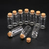 A collection of ten mini glass bottles with cork stoppers arranged on a dark surface.