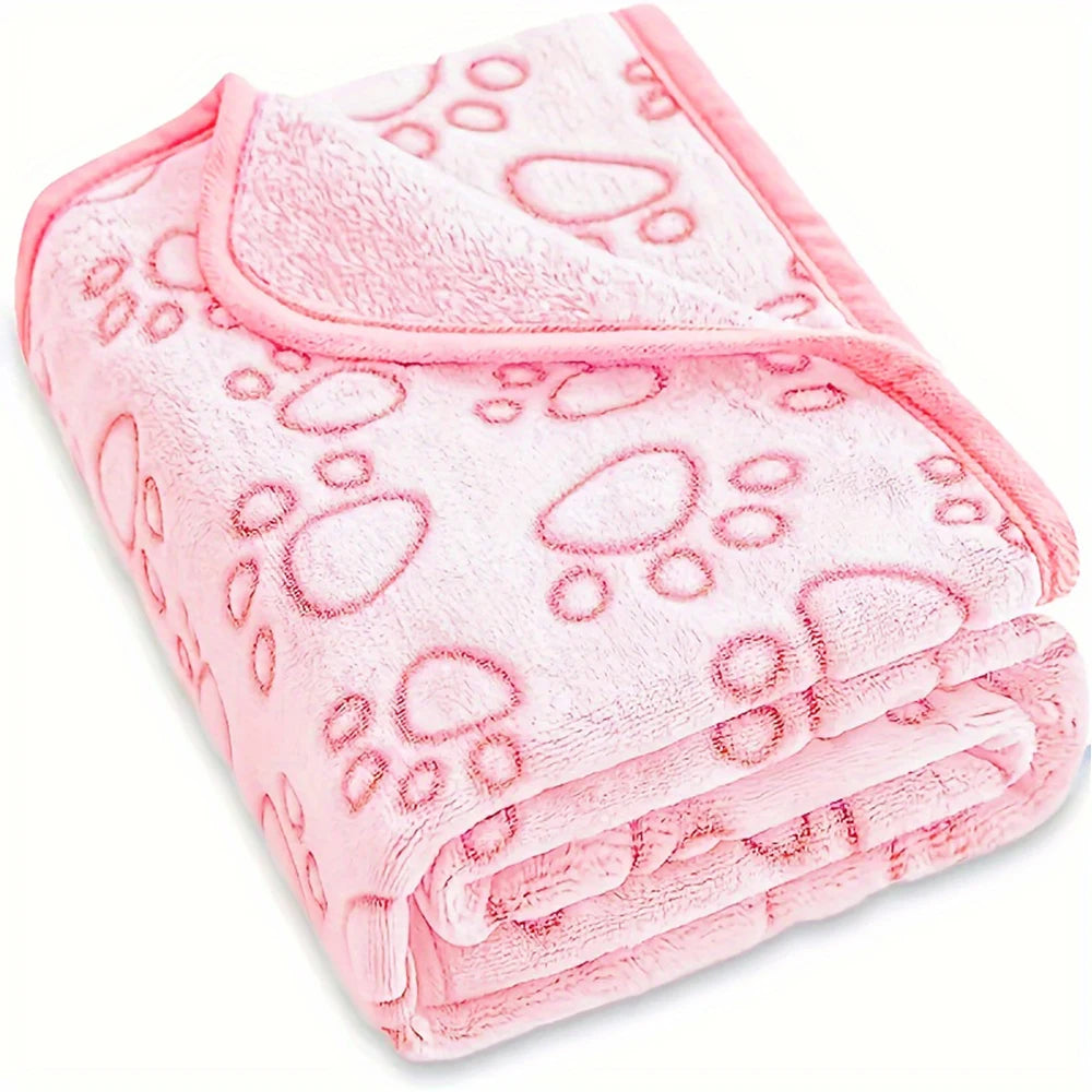 A pink ultra-soft pet blanket featuring a paw print pattern, folded and displayed.