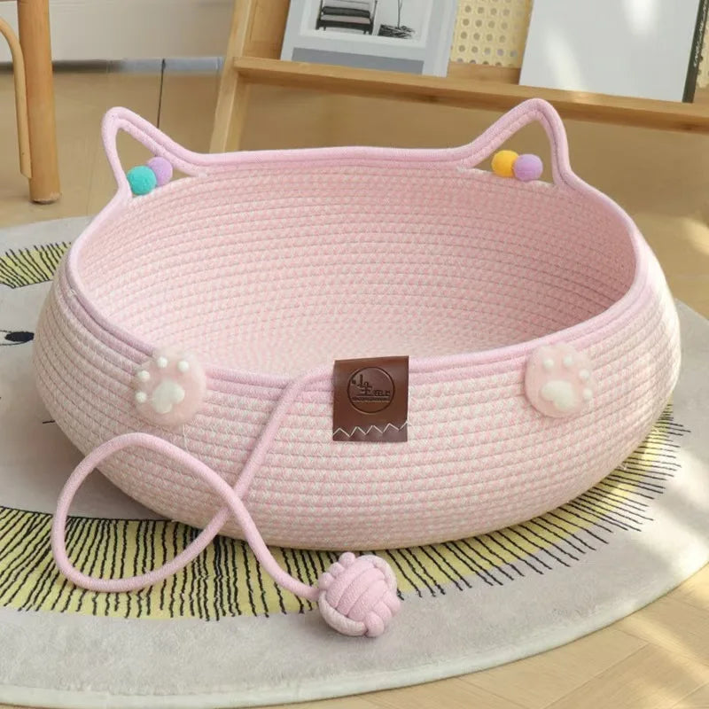 Pink 2-in-1 cat scratcher and comfort bed with play balls resting on a light rug.