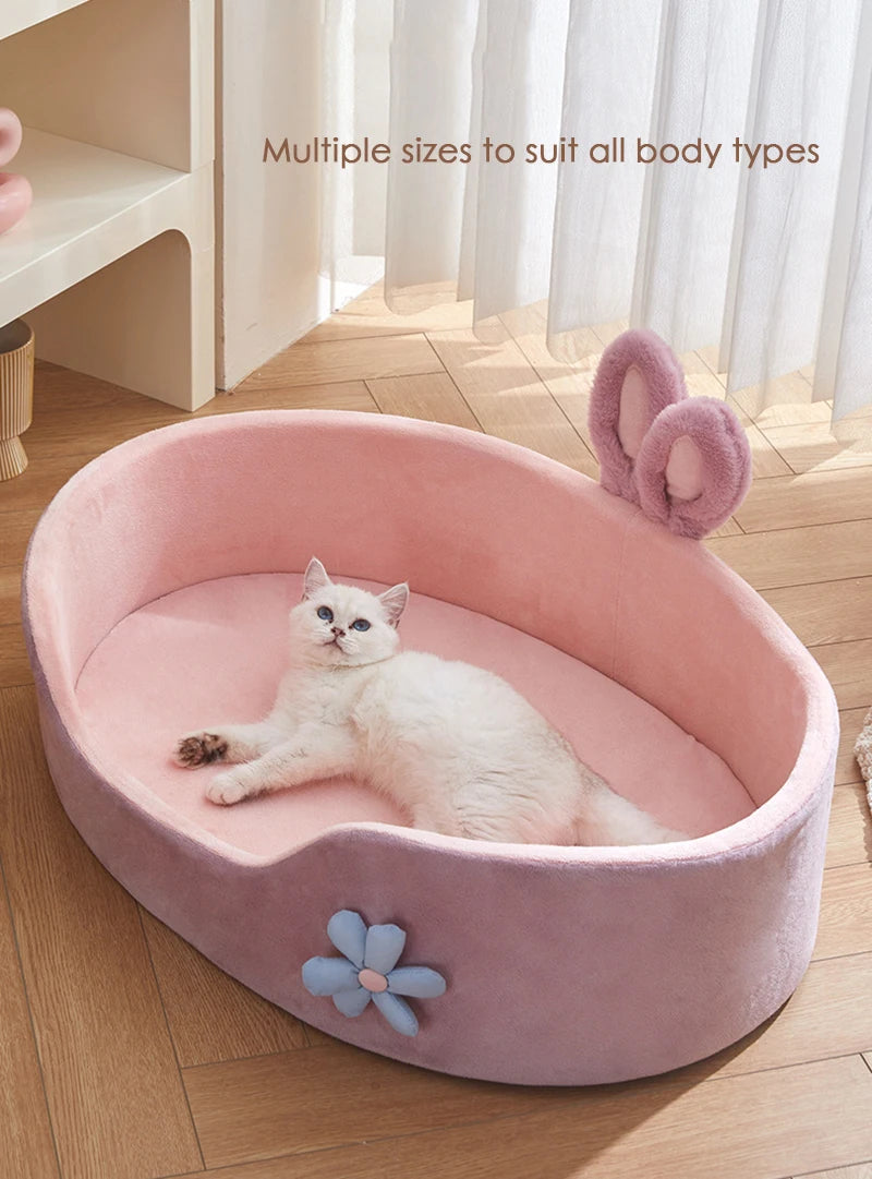 A pink plush pet bed with a removable cover is shown, featuring a white cat resting inside.