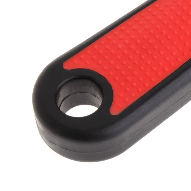 Close-up view of a red and black stainless steel pet grooming comb for dogs and cats.