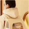Eine Person trägt einen beigen, faltbaren Hundetransporter-Rucksack mit transparentem Fenster, in dem eine Katze ist.
