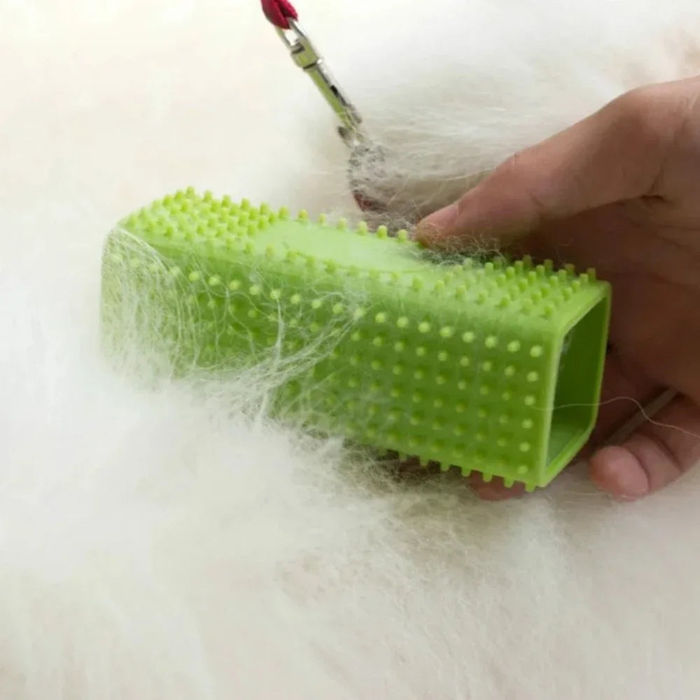 A hand holds a bright lime green silicone pet hair remover brush, with wisps of hair visible around it.