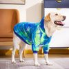Un chien de couleur claire debout sur un sol, portant un sweat à capuche en polaire tie-dye bleu et vert.