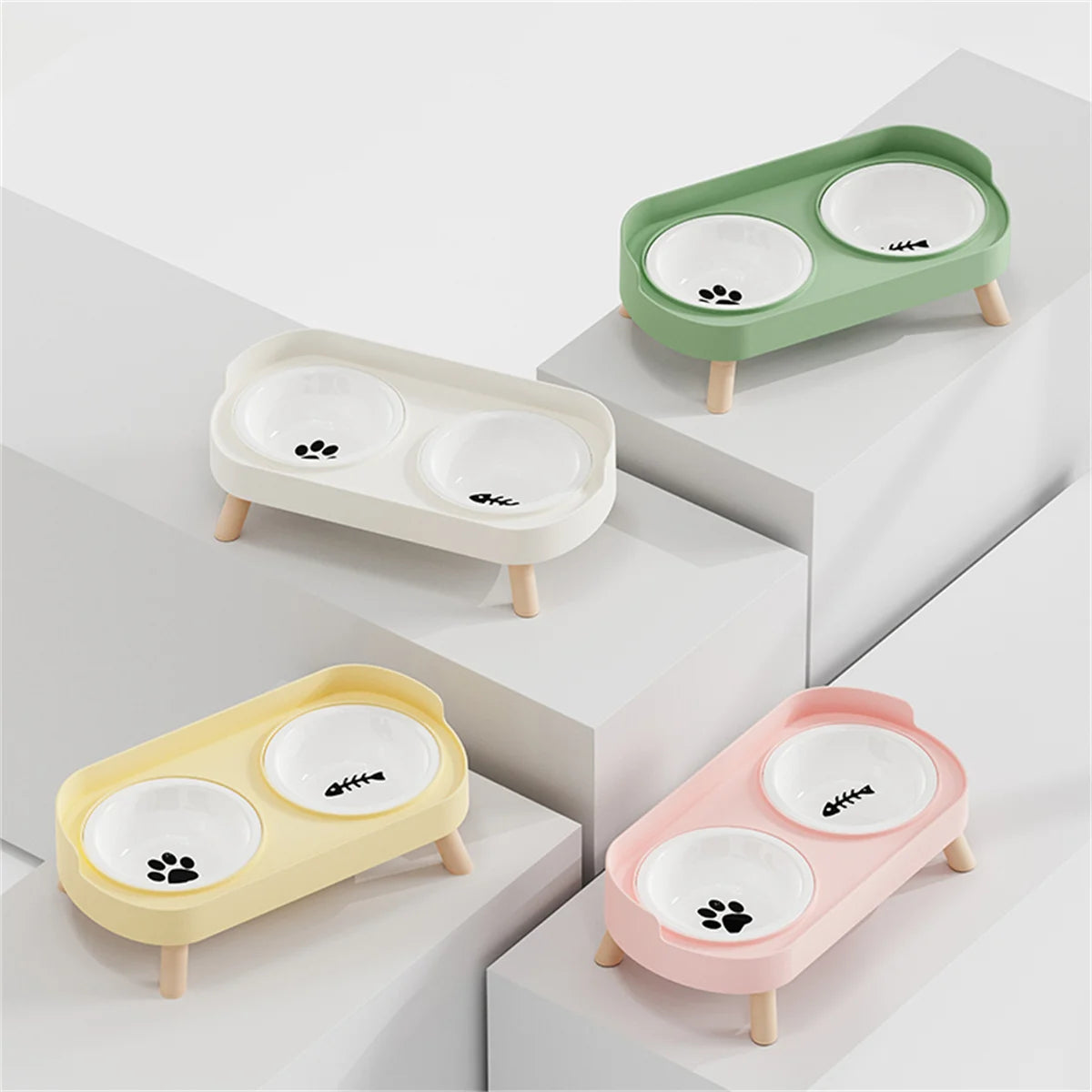 A set of three elevated ceramic double pet bowls in shades of green, white, and pink, displayed on a white surface.