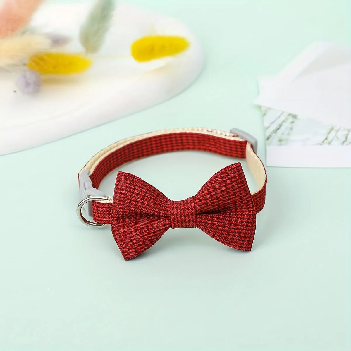 Una corbata de cuadros roja en un cuello ajustable plateado, contra un fondo verde claro.