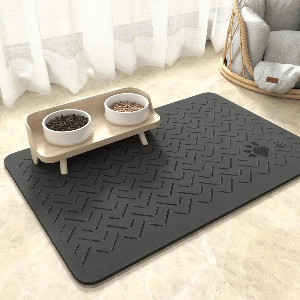 A dark gray pet feeding mat with a geometric pattern is shown on a light floor, holding two white bowls of pet food.