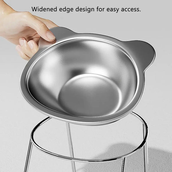 A hand is lifting an elevated stainless steel cat bowl with a widened edge design for easy access.