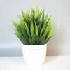 A vibrant green artificial bonsai plant in a white pot, displayed indoors.
