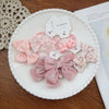 Collection de nœuds élastiques floraux roses et accessoires présentés sur une assiette blanche.