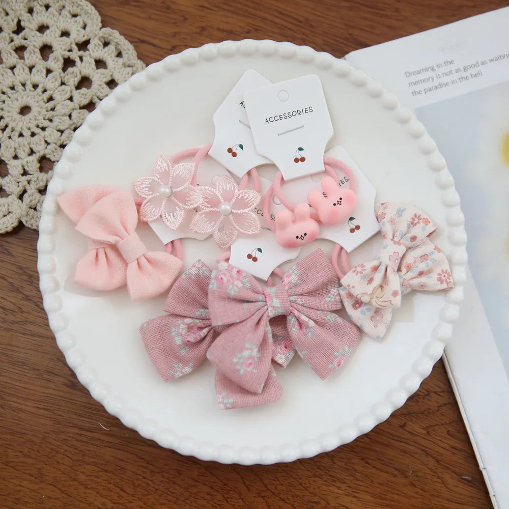 Collection de nœuds élastiques floraux roses et accessoires présentés sur une assiette blanche.