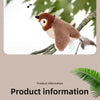 A small, realistic-looking bird toy with brown and white feathers is perched on a tree branch.