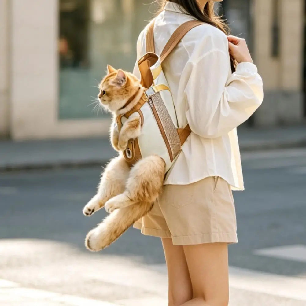 A woman is carrying a fluffy orange cat in a breathable backpack with a safety leash while walking outdoors.