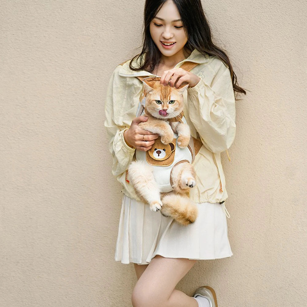 A young woman is holding a small orange tabby cat and a small dog carrier backpack.