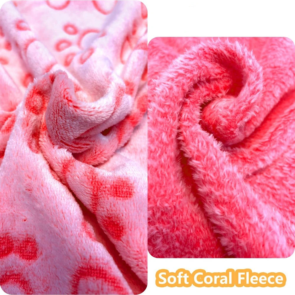 Close-up of a pink coral fleece pet blanket with red paw print patterns.