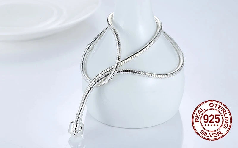 Sterling silver snake chain necklace with a heart charm displayed on a white display stand.