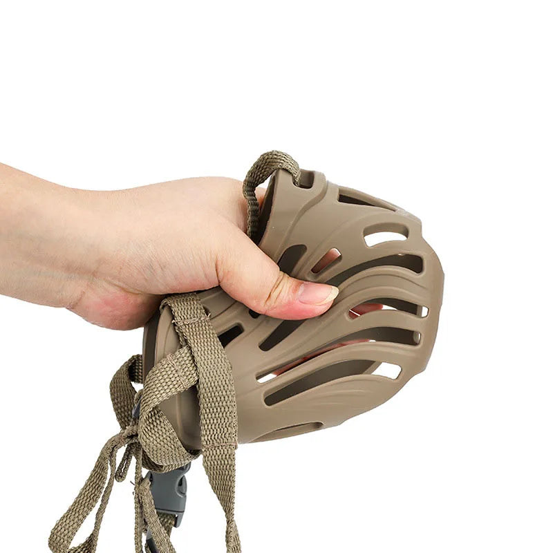 A hand is holding a beige adjustable breathable dog muzzle for small to medium dogs.