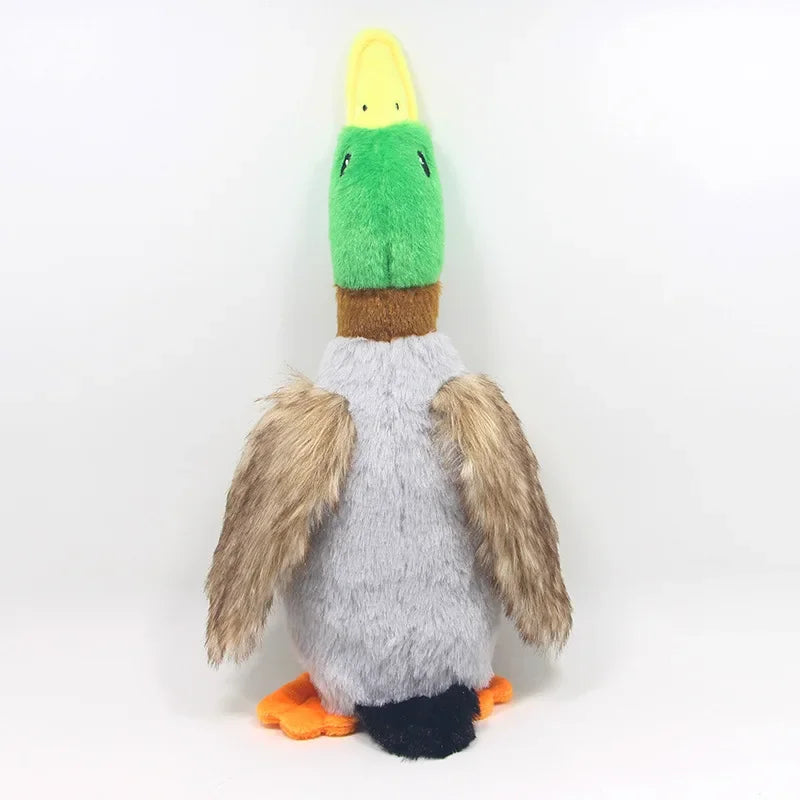A plush toy resembling a duck with a yellow beak and green body, featuring brown and gray fur and orange feet.