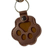 A brown leather keychain charm shaped like a cat paw print.