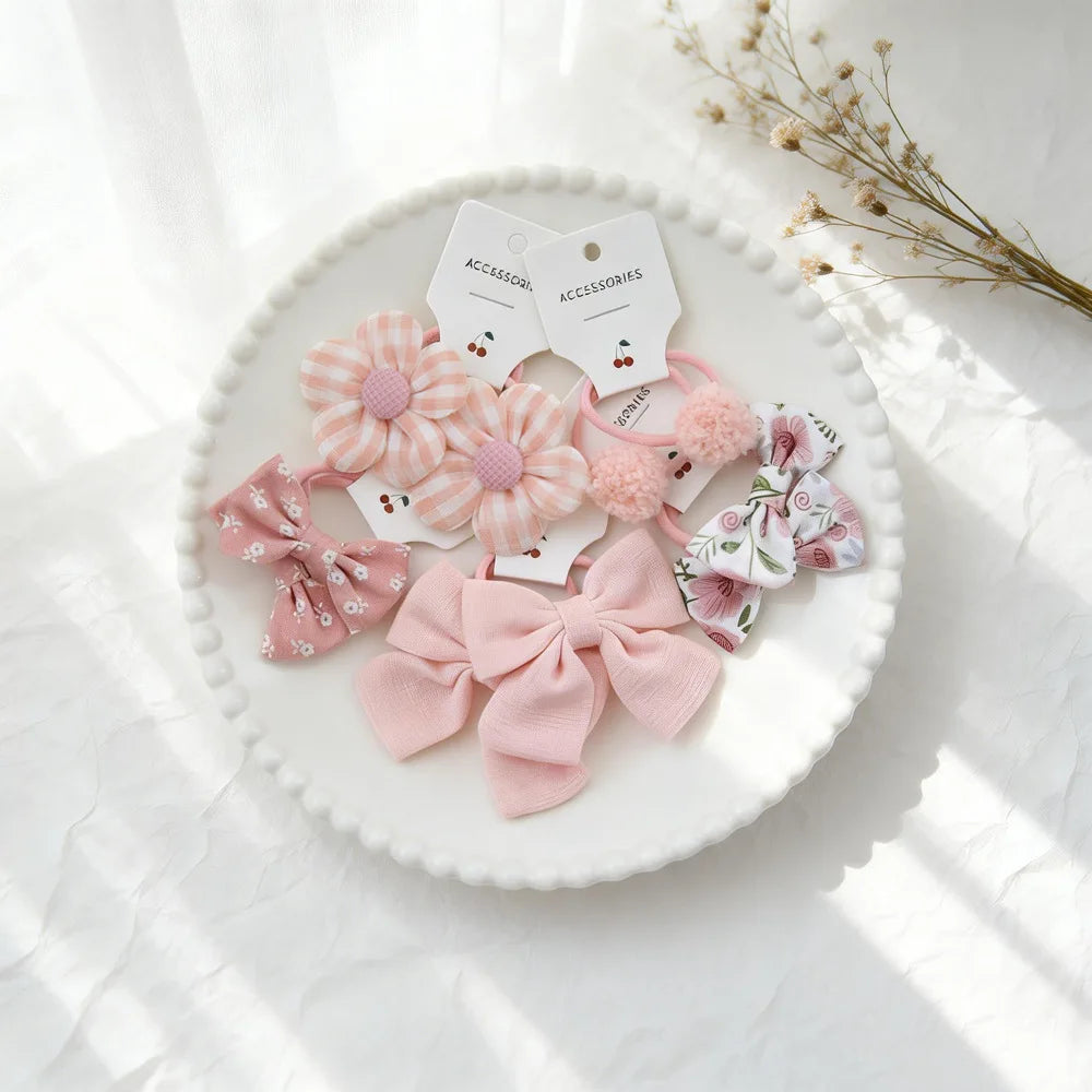 Décorations et accessoires pour cheveux roses élastiques présentés sur une assiette blanche à la lumière naturelle.