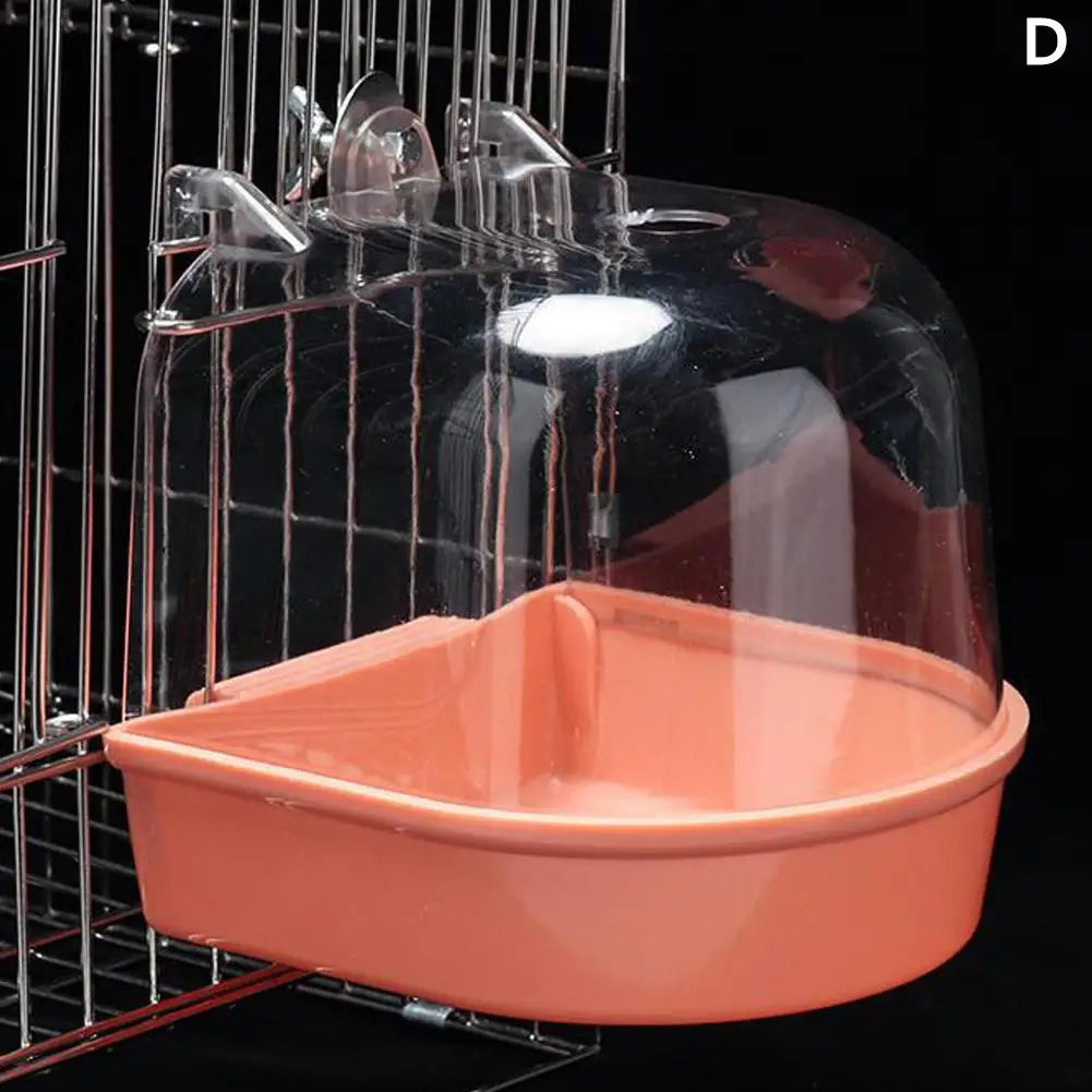 A clear hanging bird bath in an orange-colored tray is suspended within a wire cage.