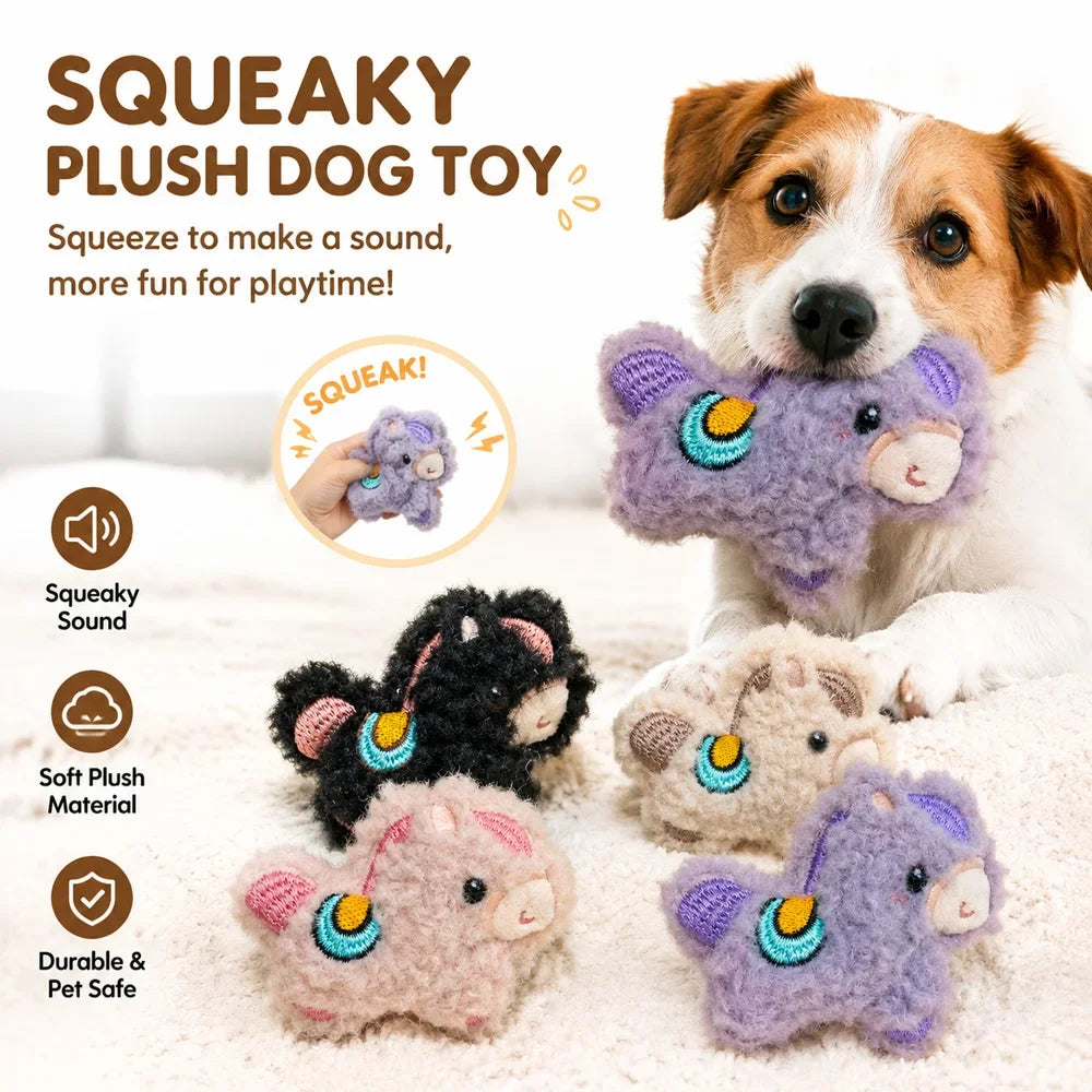 A dog is playing with a purple squeaky plush toy and other soft toys on a white surface.