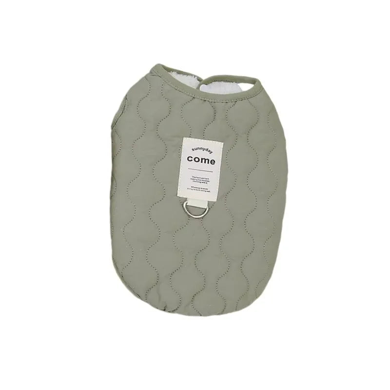 A soft sage green quilted pet vest with a white tag labeled come
