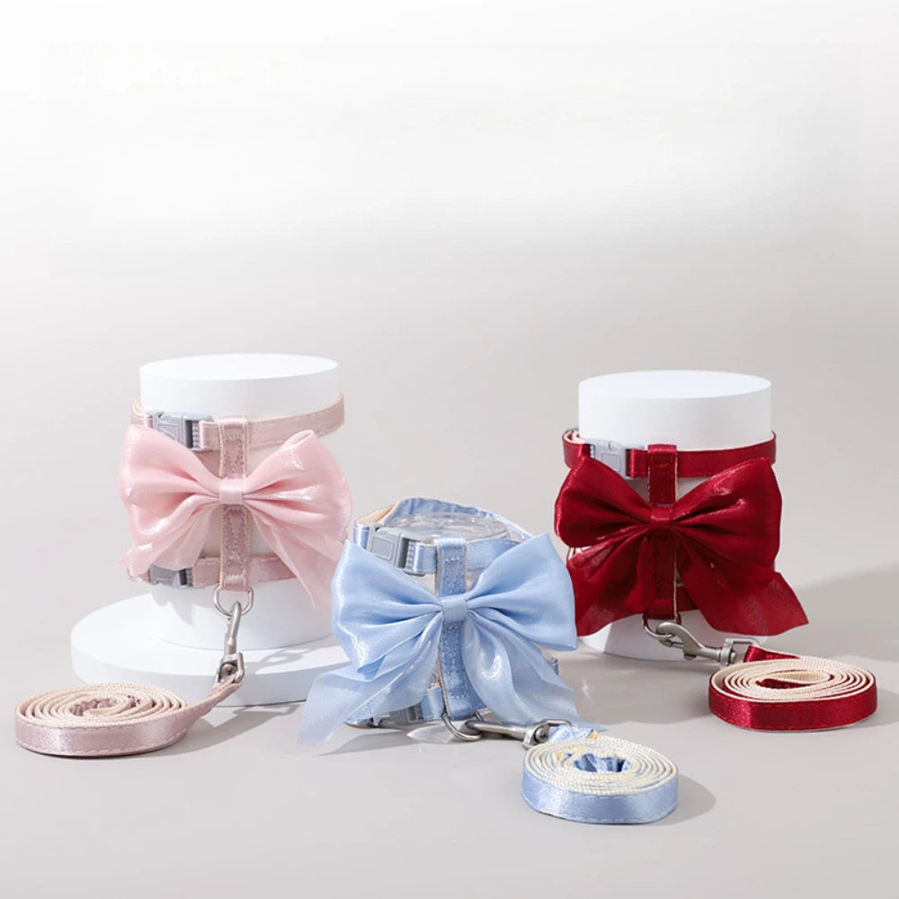 A set of adjustable cat harness and leash featuring bows in pink, blue, and red colors.