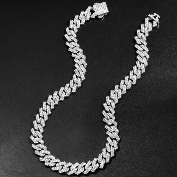 A close-up of a silver iced out Cuban link chain necklace with rhombus diamond accents displayed on a dark background.