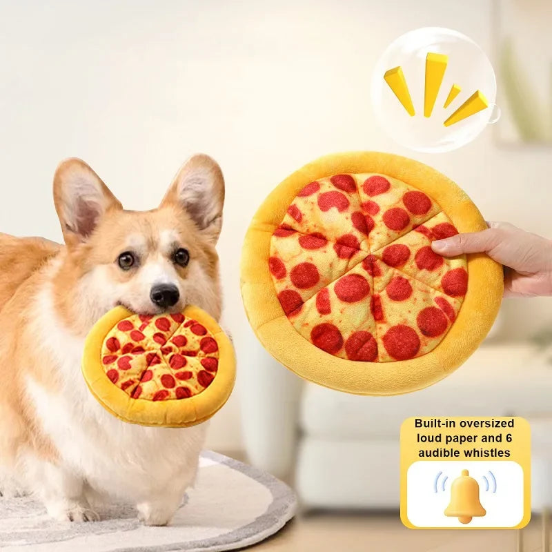 Un chien tient un jouet en peluche jaune en forme de pizza avec des garnitures rouges.