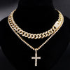 A gold-toned diamond Cuban link necklace set featuring a layered chain and a cross pendant displayed on a black velvet displa