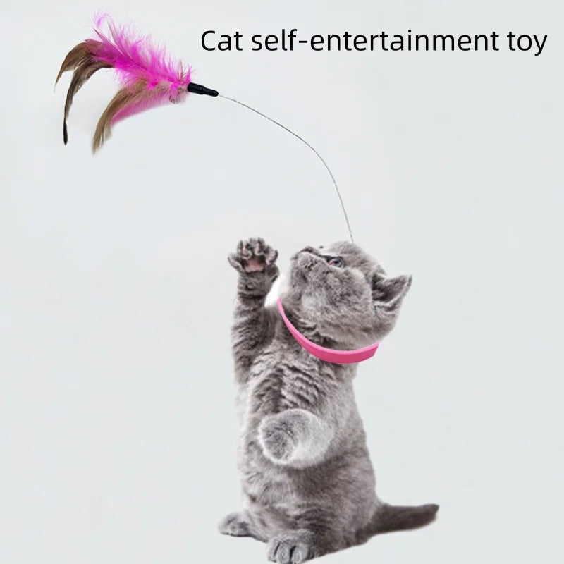 A gray kitten is playing with a pink feather toy attached to a thin string.