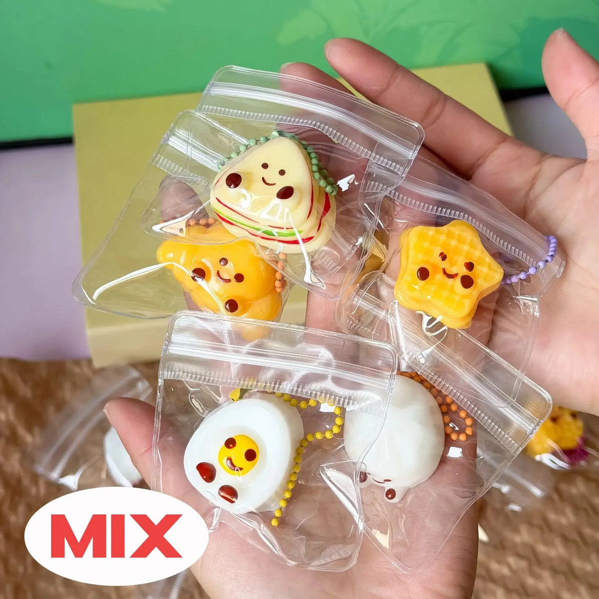 A hand holds several clear plastic bags containing various squishy bread fidget toys in yellow, white, and green colors.