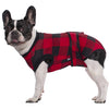 A black and white dog wearing a red and black plaid post-surgery recovery suit.