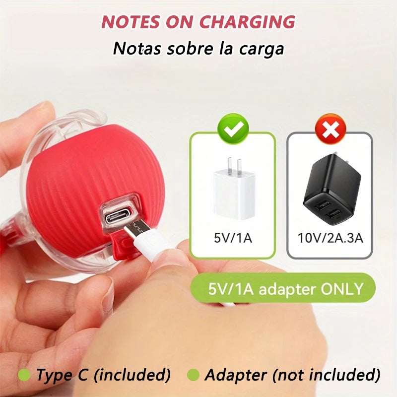 A hand holds a red self-moving cat toy ball with an attached charging cable and various power adapters.