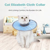 A fluffy white cat wearing a light blue Elizabethan cloth collar sits on the floor.