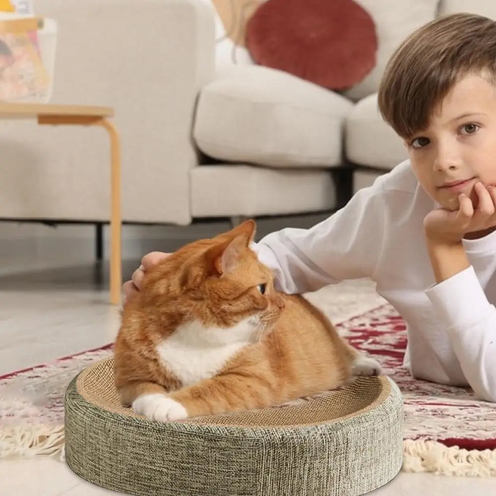 An orange and white cat is resting on a woven oval scratching board in a bright indoor setting.