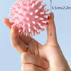 A hand holds a pink, spiky rubber ball designed for dental cleaning and chewing.