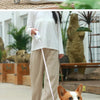 An orange and white LED retractable dog leash is shown next to a dog outdoors.