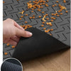 A hand places a black rubber backing onto a dark mat, demonstrating the anti-leaking and anti-slip features.