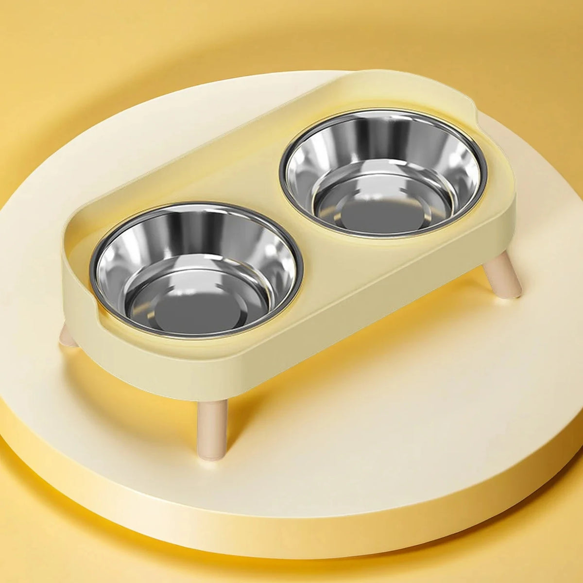 A light yellow elevated pet feeder with two stainless steel bowls sits on a round platform.