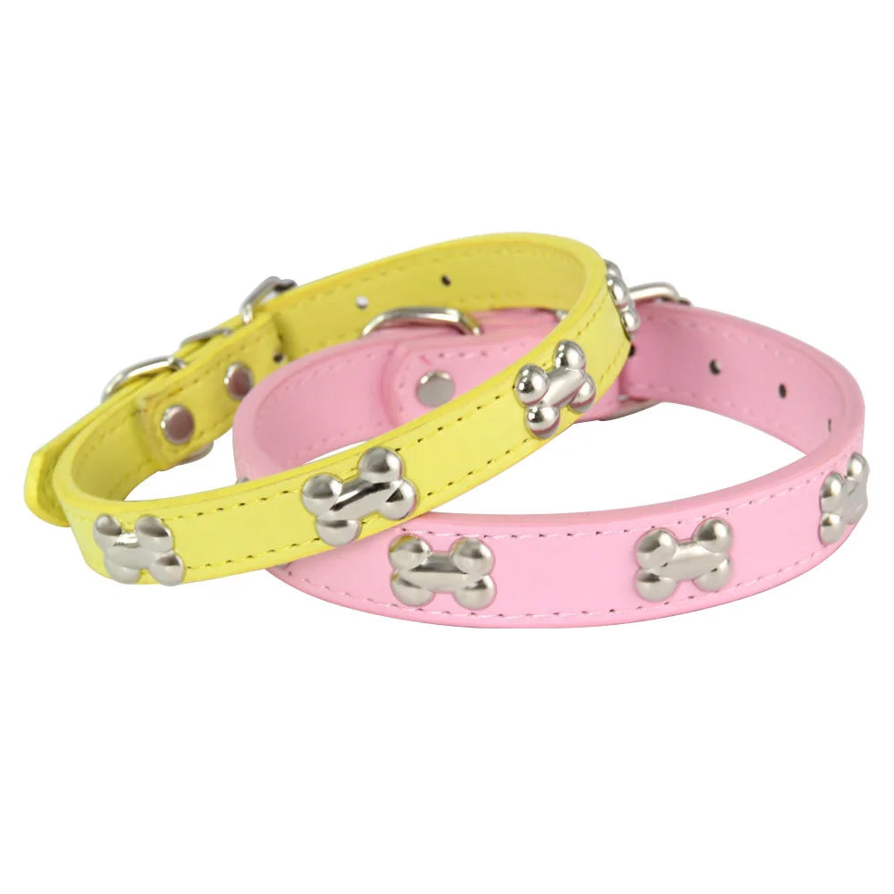 A pair of colorful padded leather dog collars, one yellow and one pink, featuring silver bone rivets.