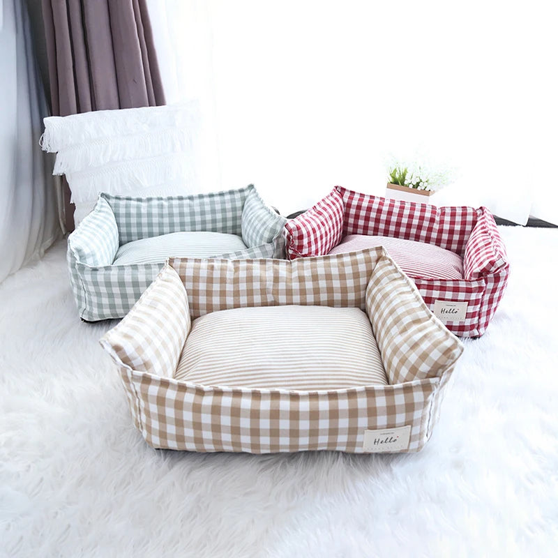 Un cosy lit pour animal en coton beige et blanc à carreaux posé sur un tapis blanc moelleux.