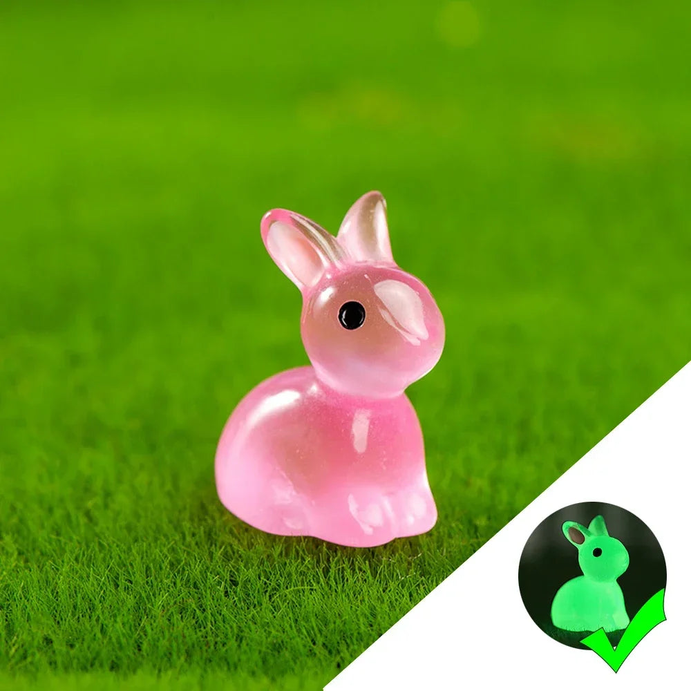 A pink resin bunny figurine resting on bright green grass.