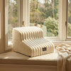 A cream-colored pet safety ladder for dogs and cats resting on a windowsill with blurred greenery in the background.