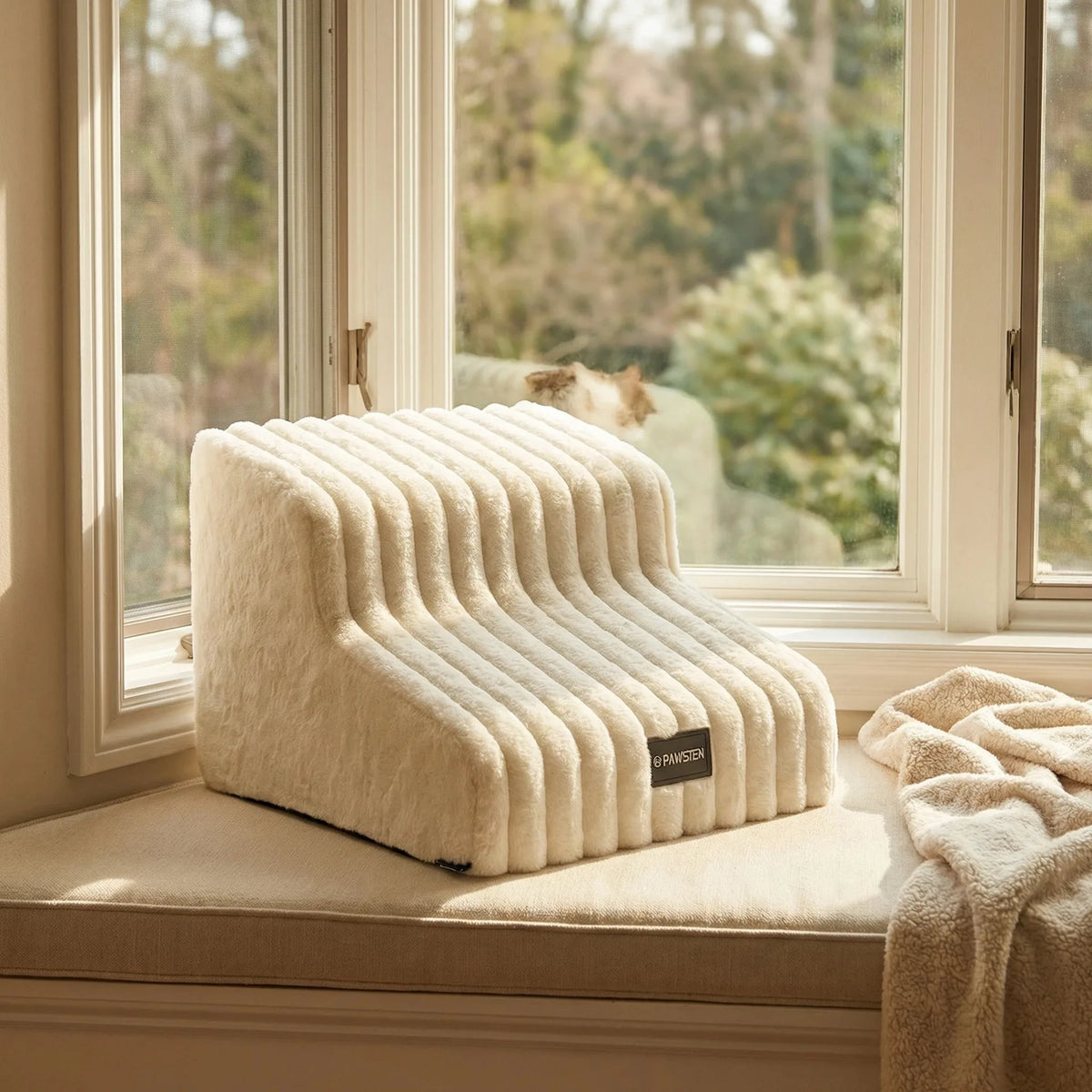 A cream-colored pet safety ladder for dogs and cats resting on a windowsill with blurred greenery in the background.