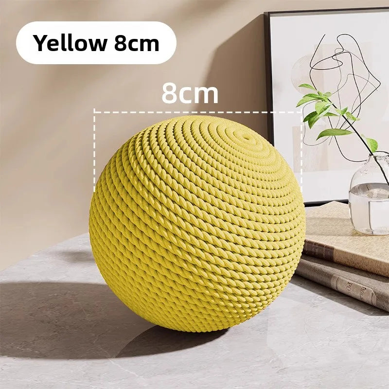 A bright yellow sisal cat toy ball with a rattle, shown on a light surface.