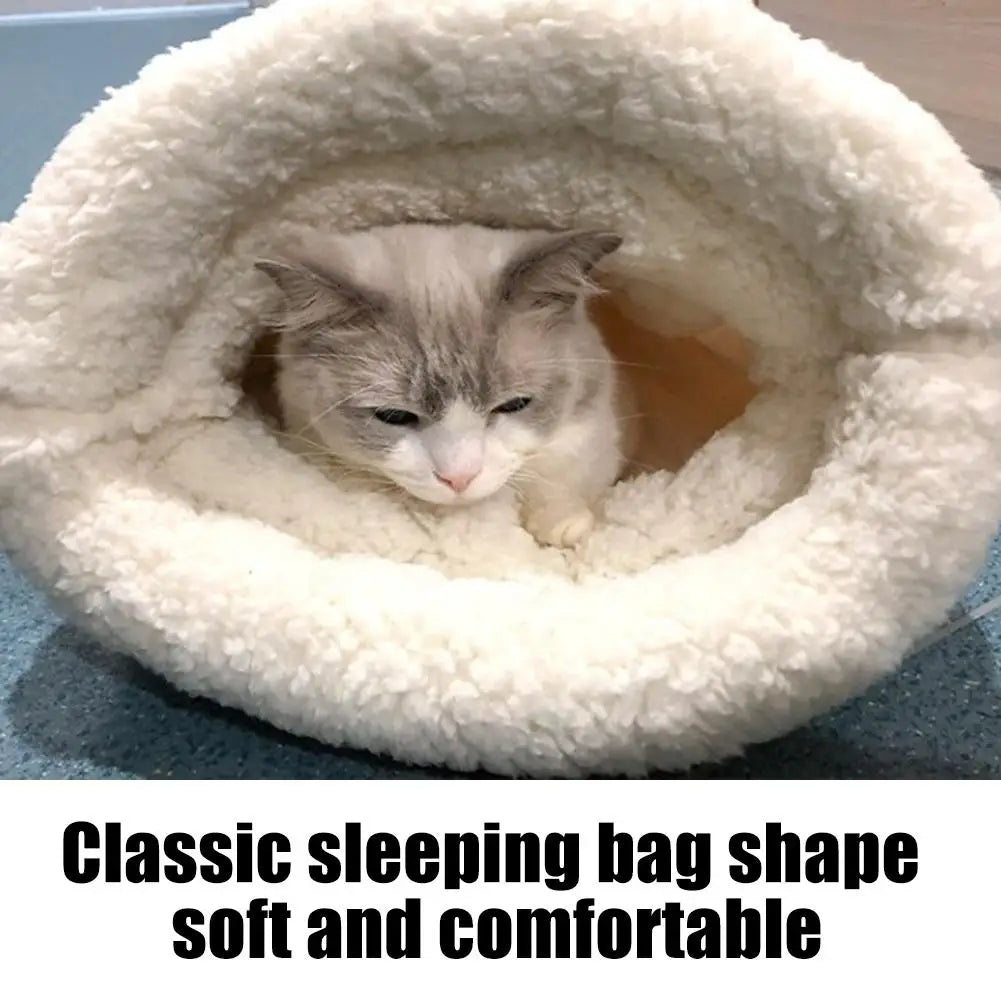A fluffy white sleeping bag shaped like a tunnel, with a small gray cat peeking out from the entrance.