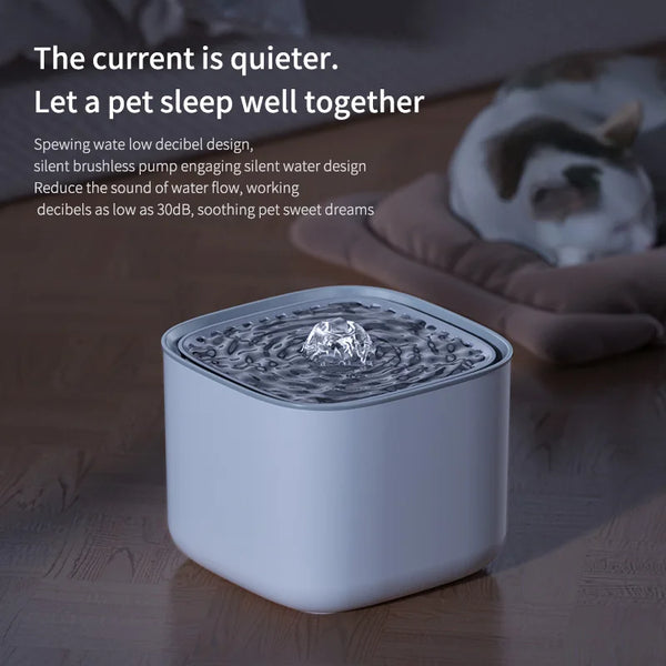 A white automatic cat water fountain with flowing water is placed on a wooden surface next to a cat.